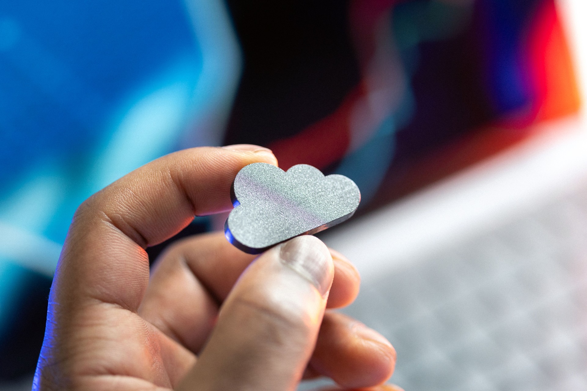 Hand holding a cloud icon on defocused futuristic background representing modern cloud technologies and cloud service
